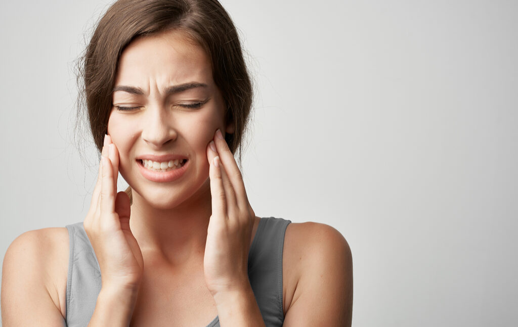Woman holding her jaw seeking Botox for jaw pain relief